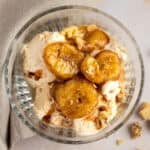 Air fryer bananas served on top of ice cream, sprinkled with walnuts.