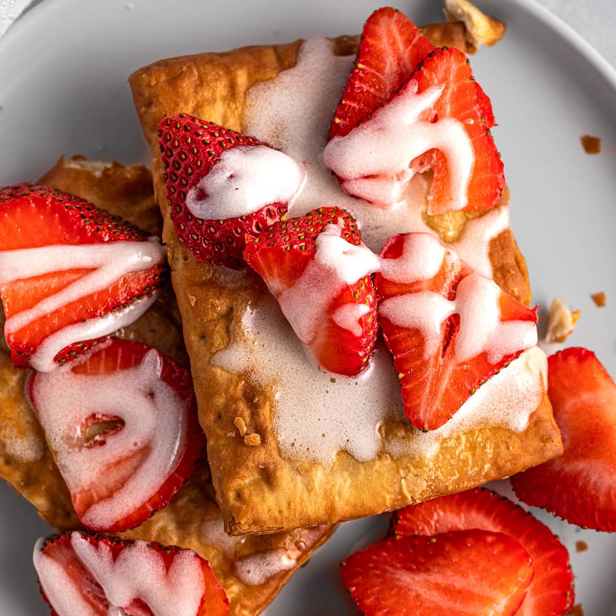 An air fryer toaster strudel topped with icing and fresh strawberry slices.