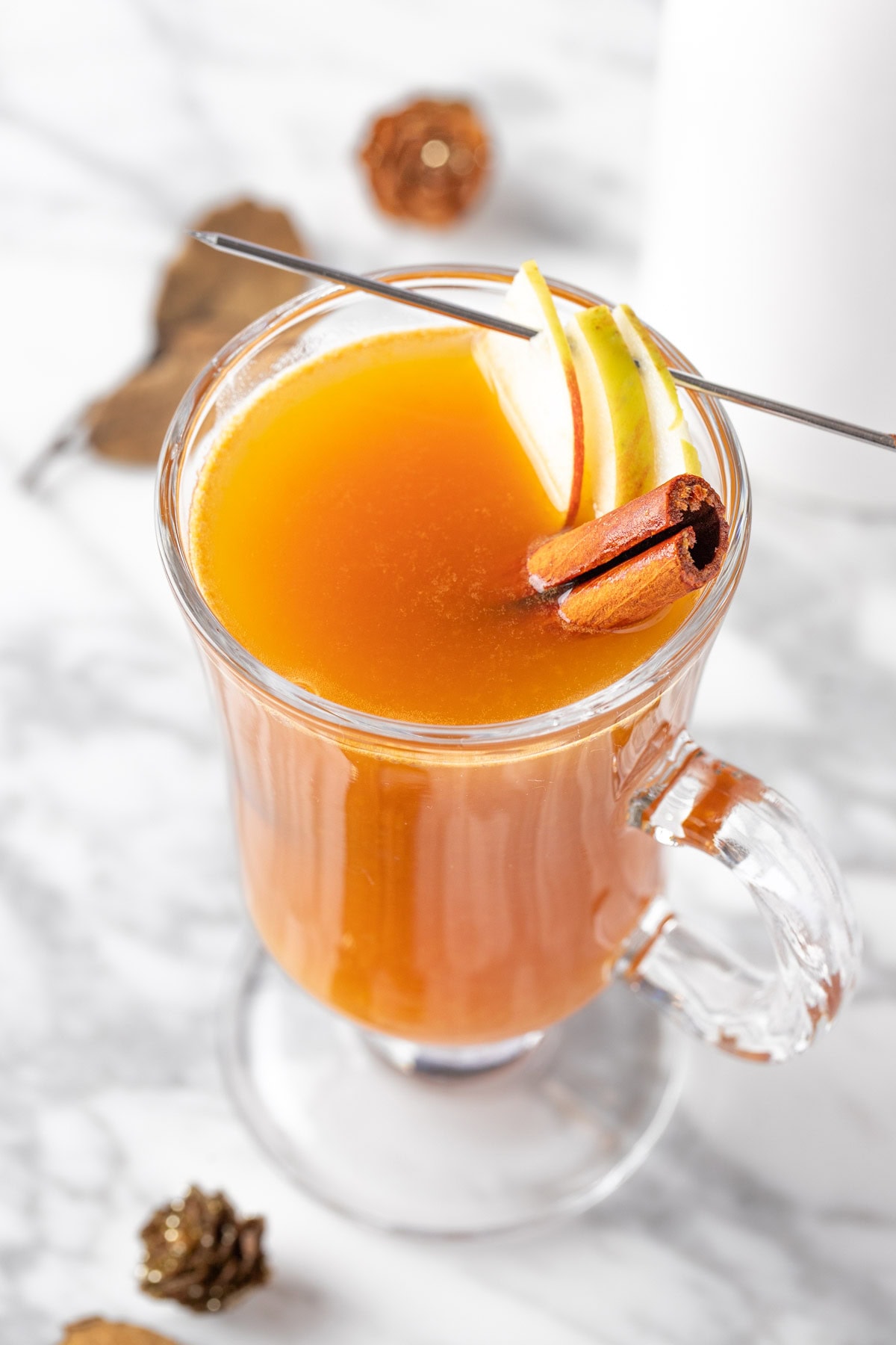 Overhead view of an apple cider hot toddy on a white marble table.