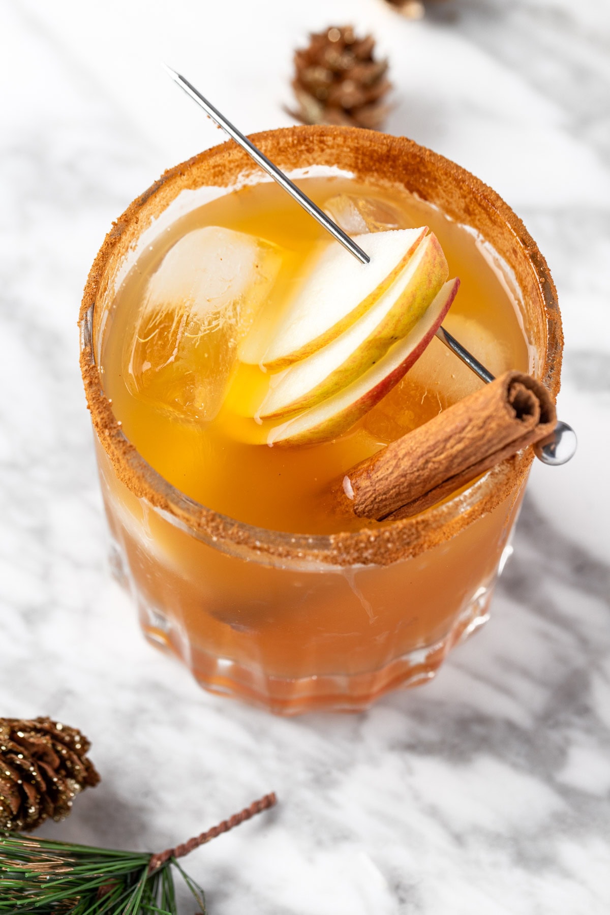 A fall margarita garnished with apple slices and a cinnamon stick.