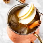 Overhead view of an apple cider moscow mule garnished with apple slices and a cinnamon stick.