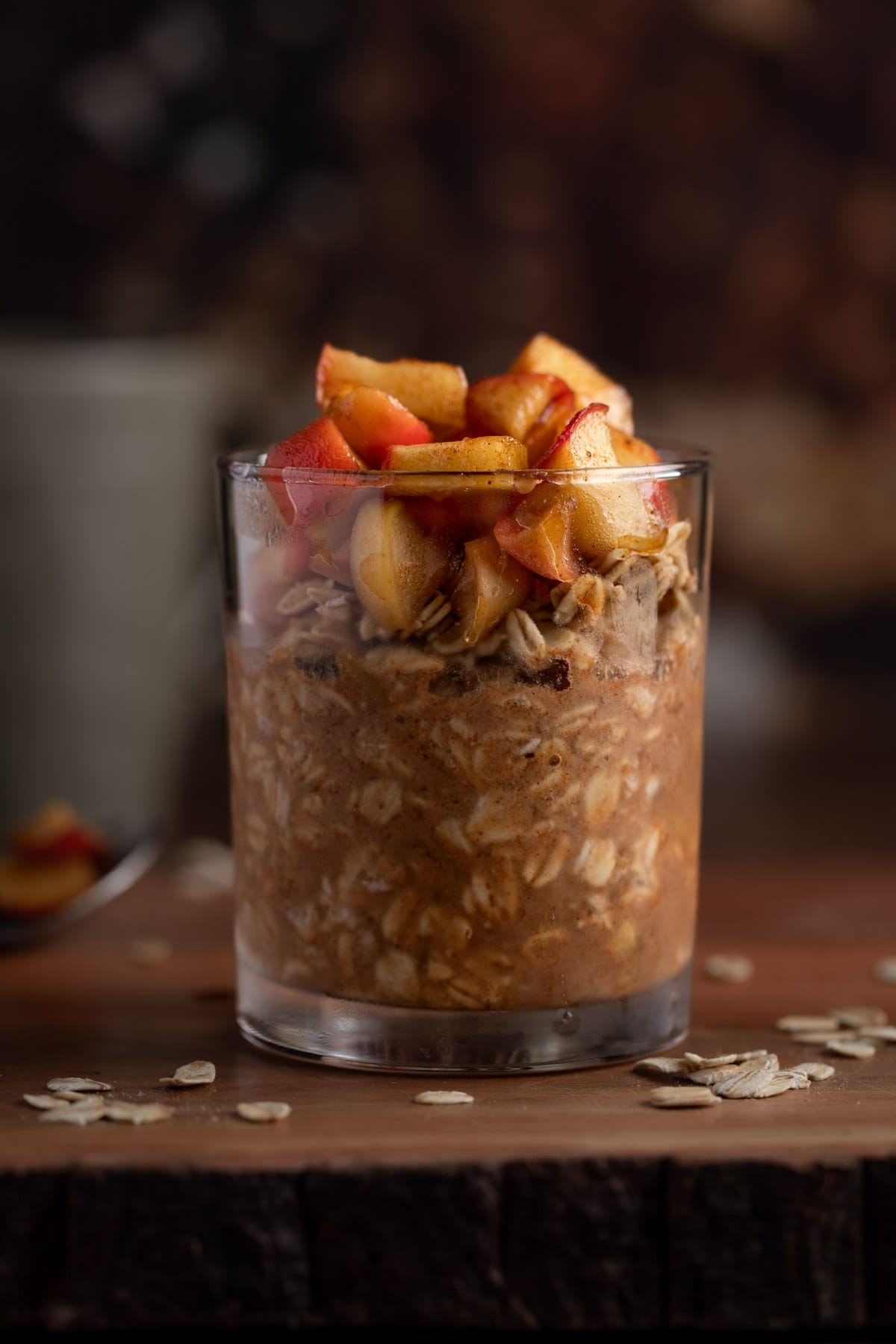 Eye level view of apple pie oats in a jar, sitting on a wooden table.