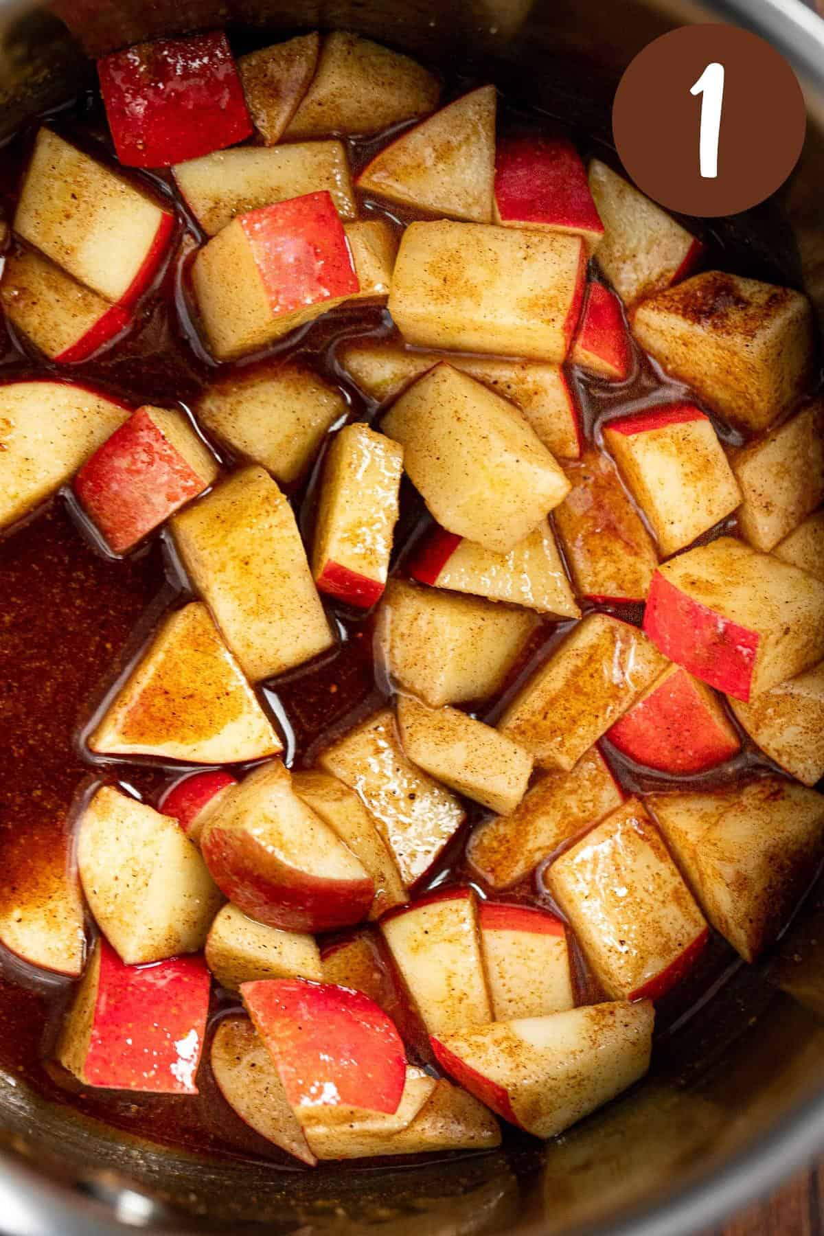 A process photo illustrating step 1: The apples, maple syrup and spices being cooking in a saucepan.