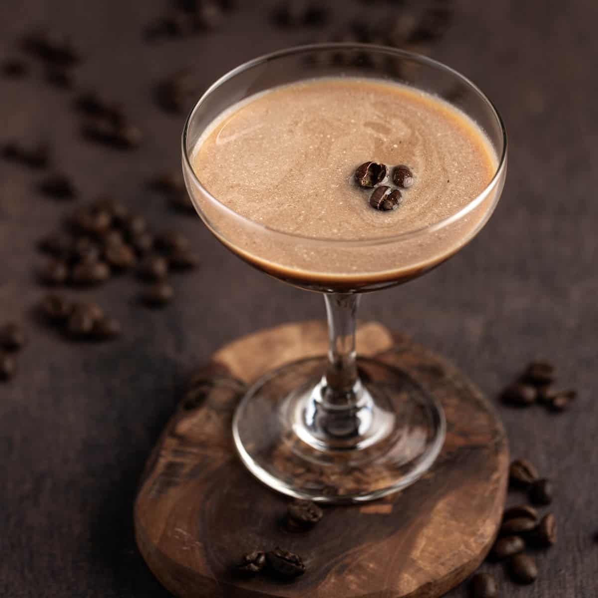 A coupe glass of baileys martini espresso, sitting on a wooden coaster. 