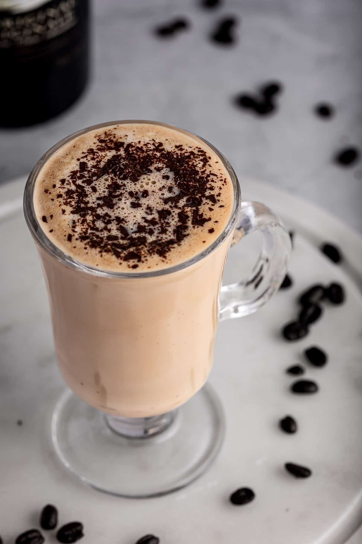 A Baileys latte topped with a sprinkle of cocoa powder, sitting on a white marble board.