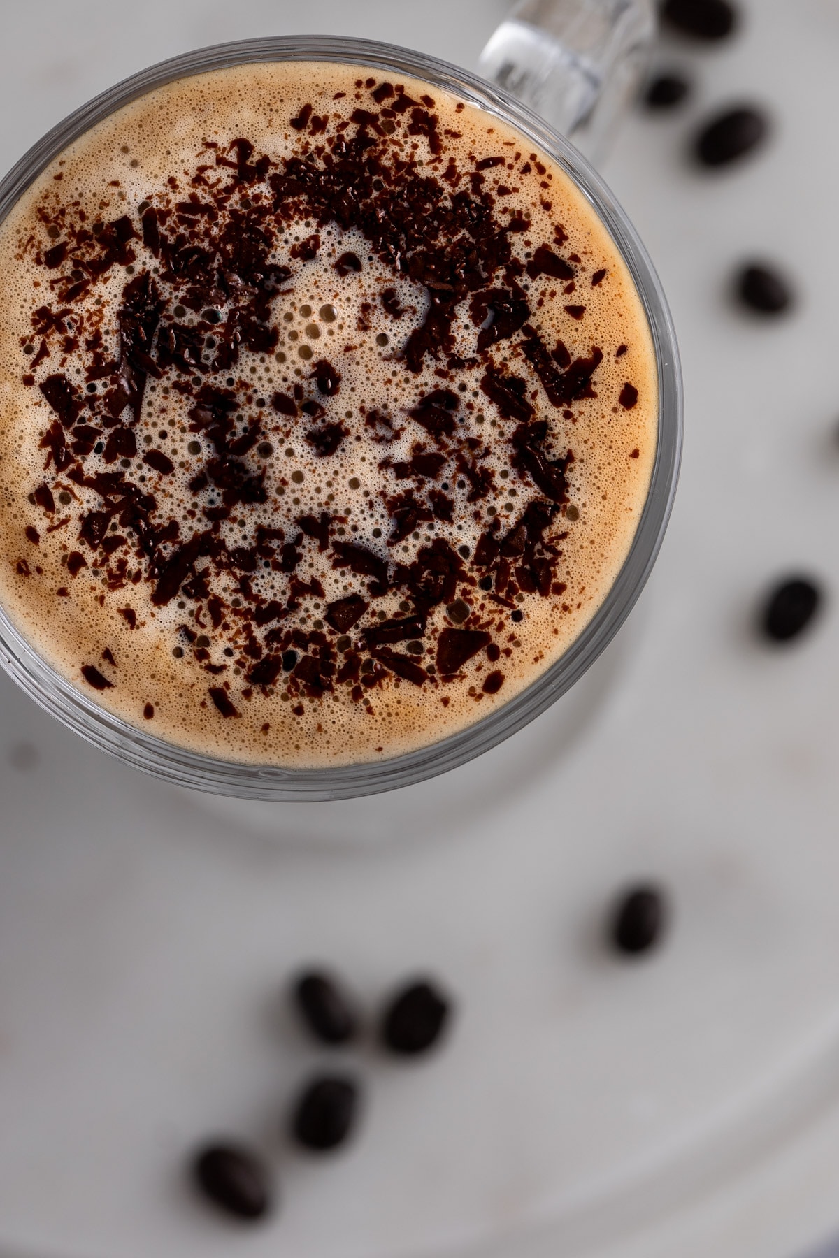 Overhead view of the baileys latte sprinkled with chocolate shavings, on a white background.