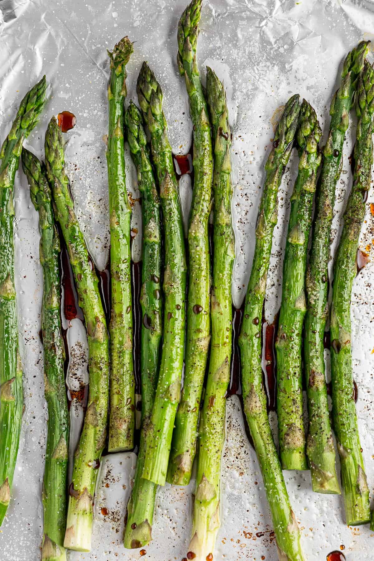 A bunch of balsamic glazed asparagus on a tray covered with aluminum folder.