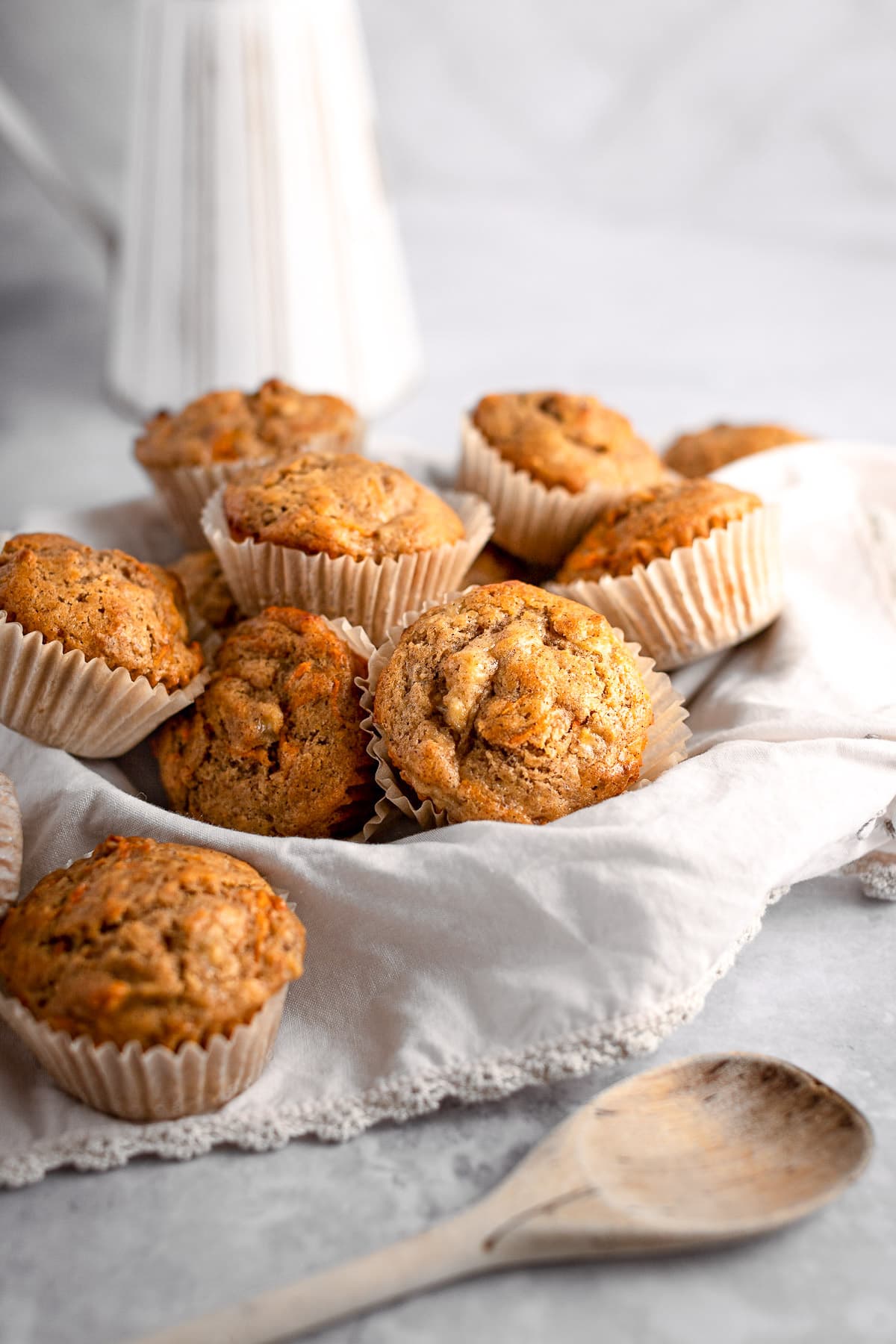 A basket filled with banana carrot muffins, sitting on a light grey table.