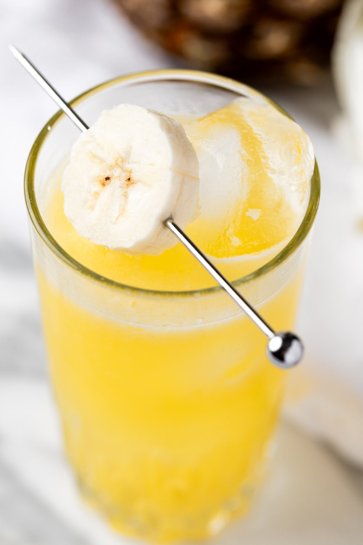 A banana rum cocktail garnished with banana slices.