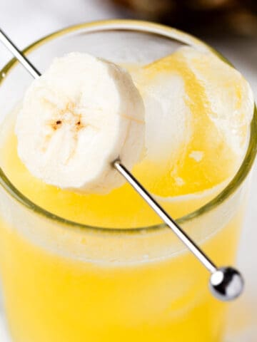 A banana rum cocktail garnished with banana slices.