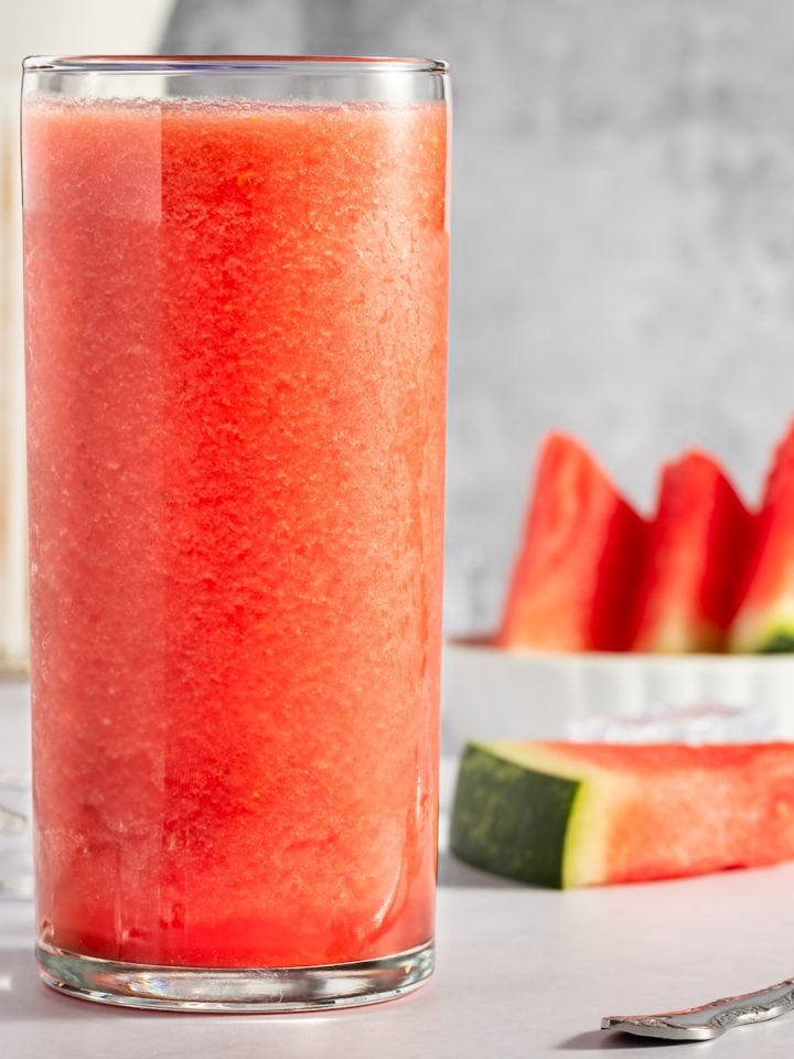 Up close photo of banana watermelon smoothie, surrounded by ice cubes and watermelon slices.