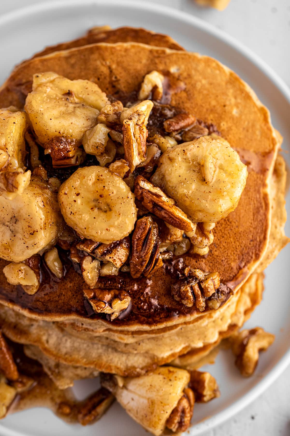Overhead view of the bananas foster topping sauce on top of a stack of pancakes.