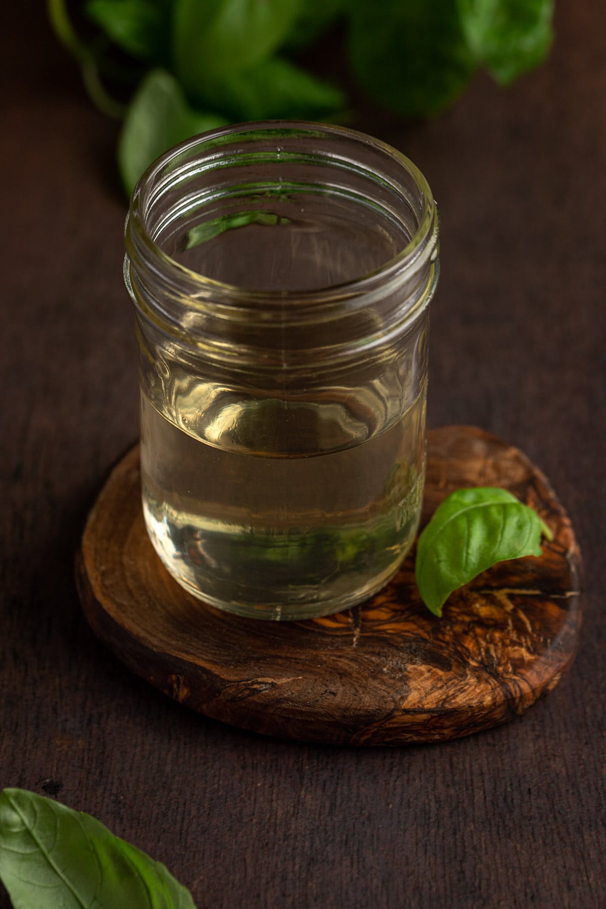 Basil simple syrup in a mason jar on a wooden table.