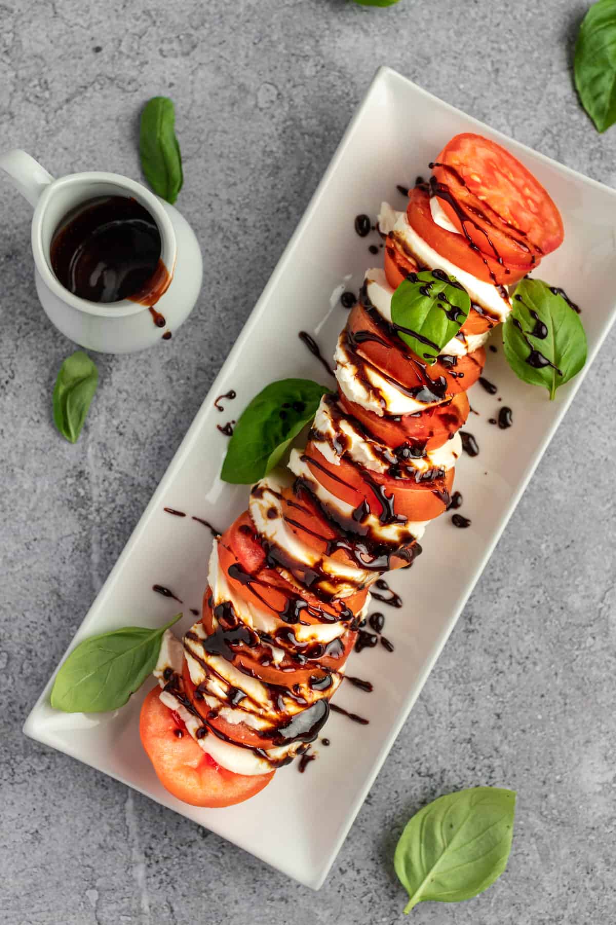 Overhead view of tomatoes and mozzarella drizzled with balsamic glaze for caprese salad.