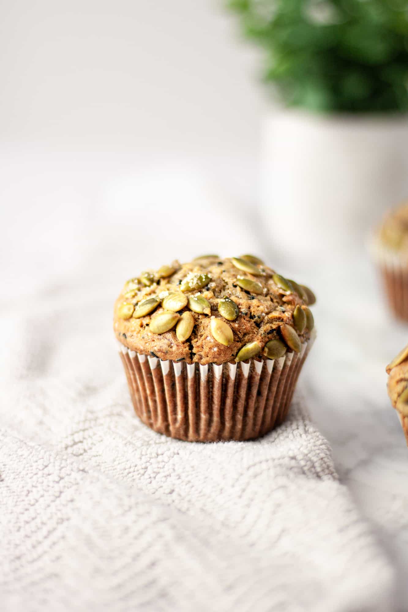 Up close view of a black sesame muffin with pumpkin seeds and turbinado sugar on top