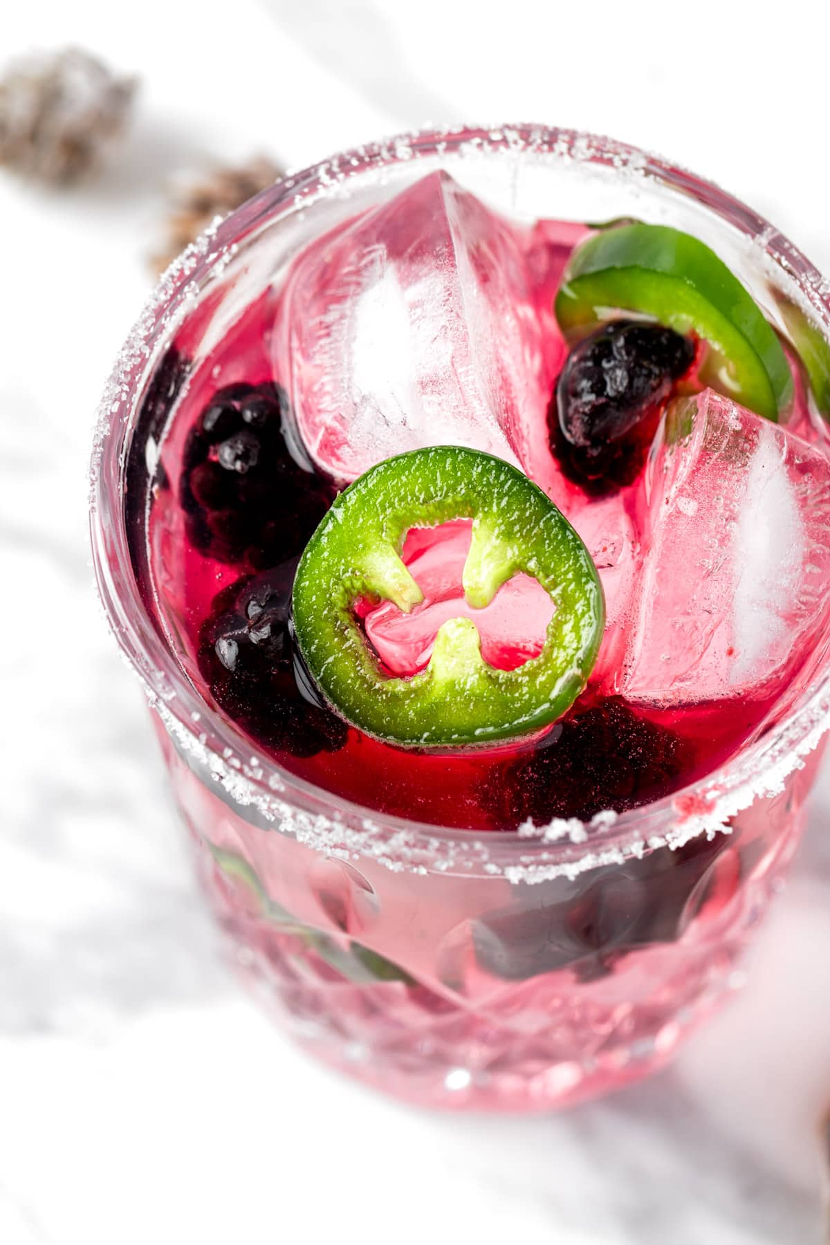 A blackberry jalapeno margarita garnished with blackberries and jalapeno slices.