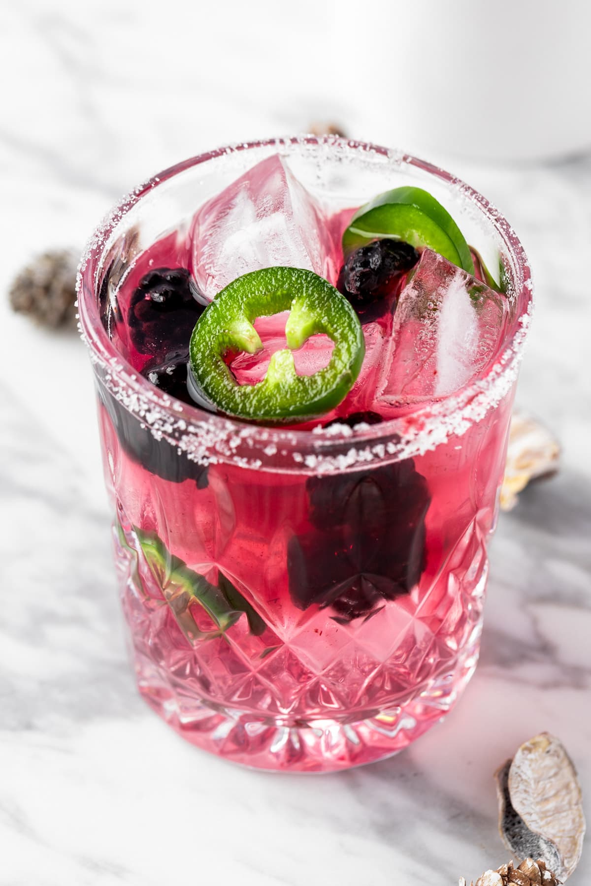 A spicy blackberry margarita garnished with jalapenos and blackberries.