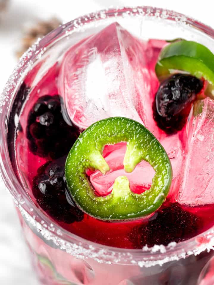 A blackberry jalapeno margarita garnished with blackberries and jalapeno slices.