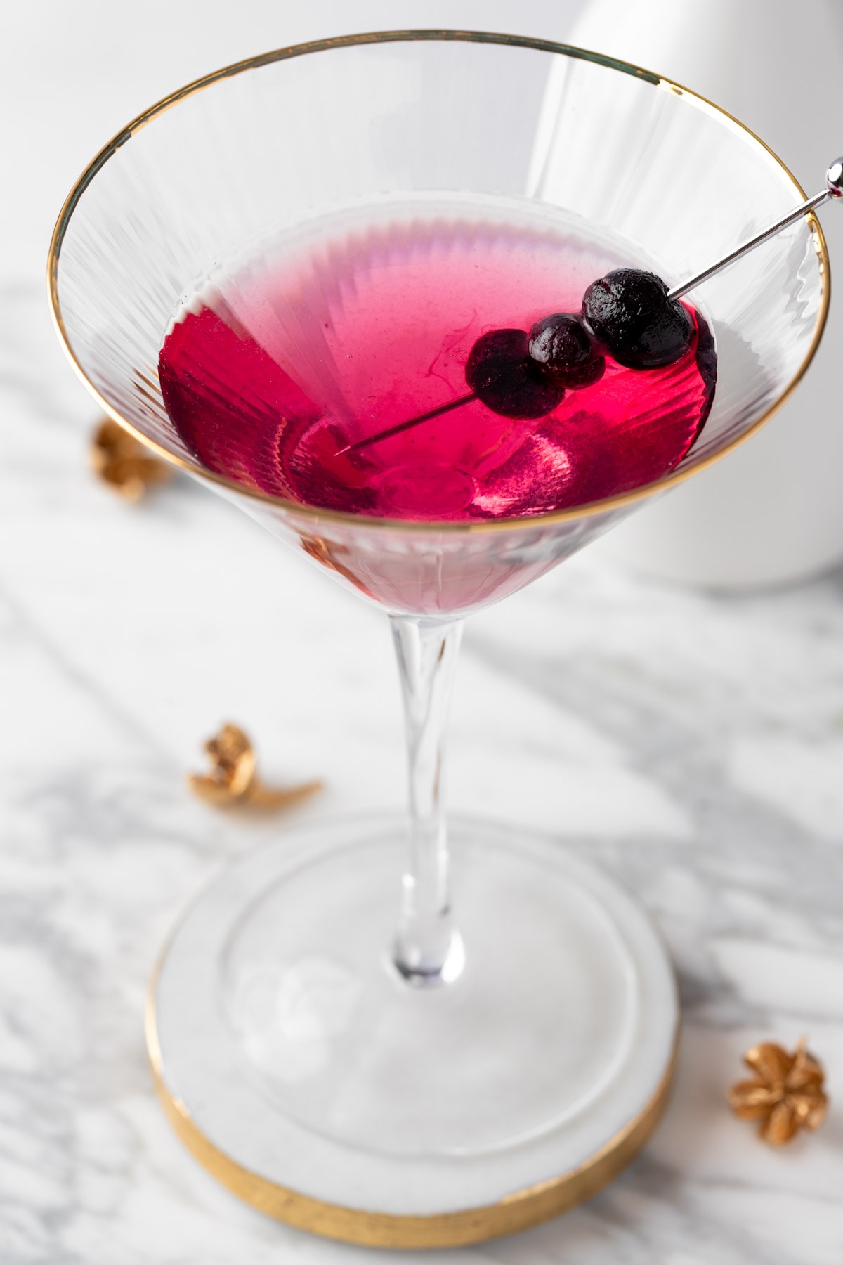 A blueberry lemon drop martini on a white marble table.