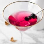 A blueberry lemon drop martini on a white marble table.