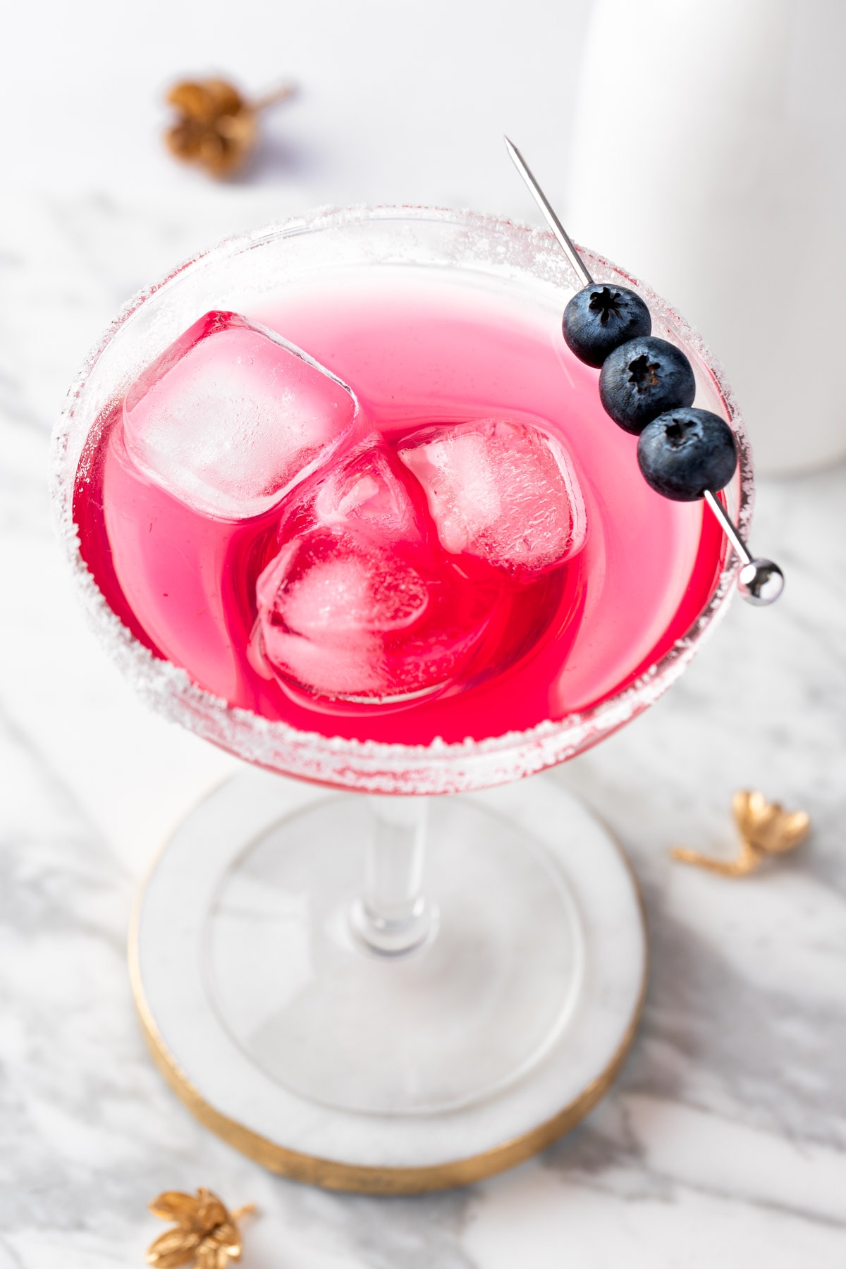 A blueberry lemonade margarita garnished with blueberries on a white background.