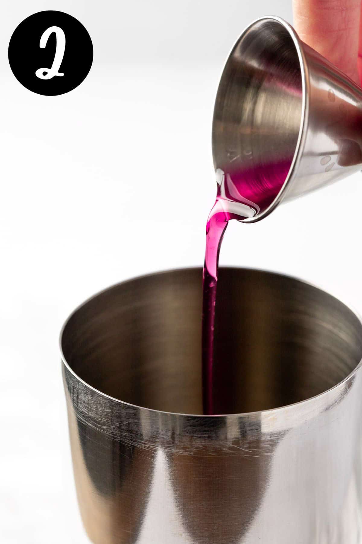 Pouring the blueberry syrup into the cocktail shaker.