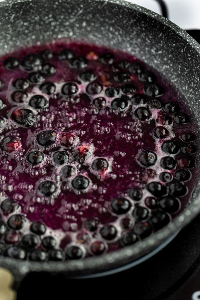 Blueberries simmering in a saucepan as they form blueberry syrup.