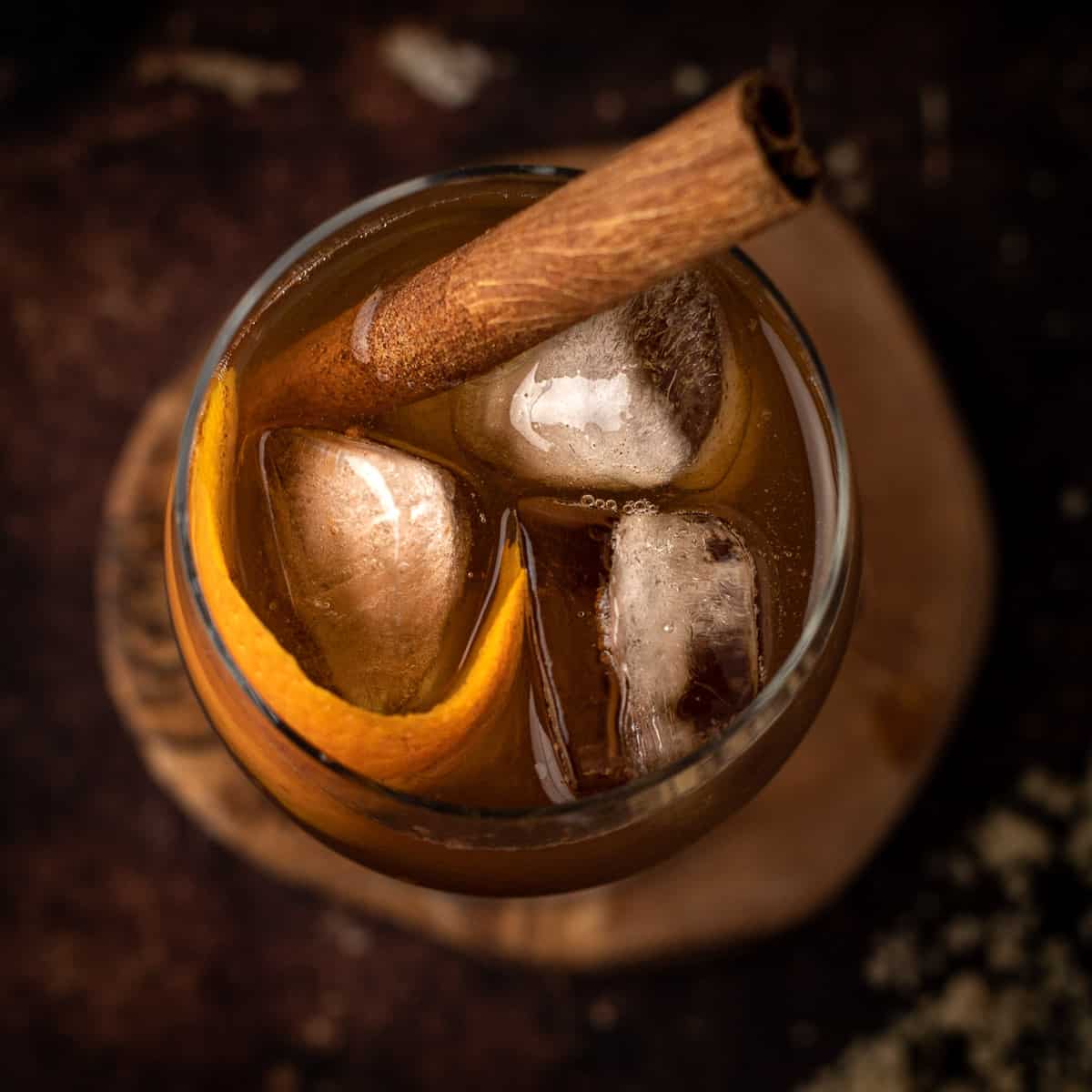 Overhead view of an old fashioned bourbon cocktail garnished with a cinnamon stick and orange peel. 