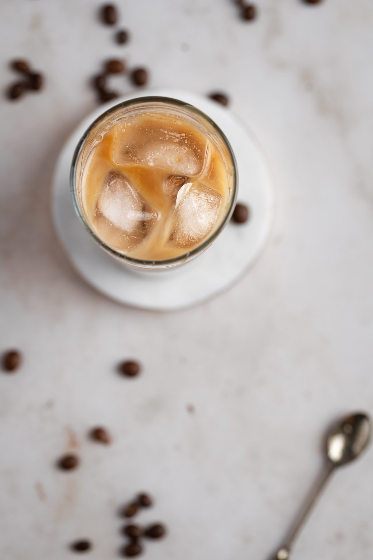 Overhead view of an iced caramel coffee on a white marble table.