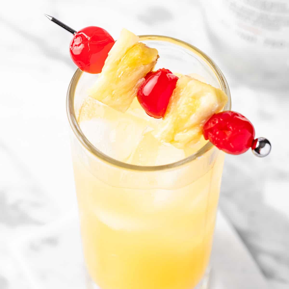 A Caribou Lou Cocktail garnished with cherries and pineapple slices.