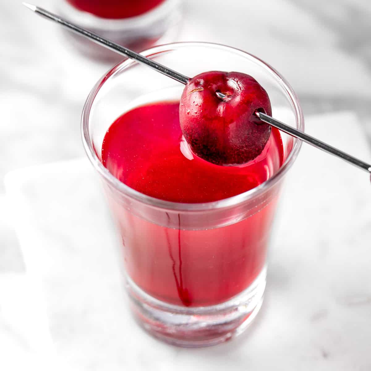 A red Cherry Vodka Shot garnished with a cherry.