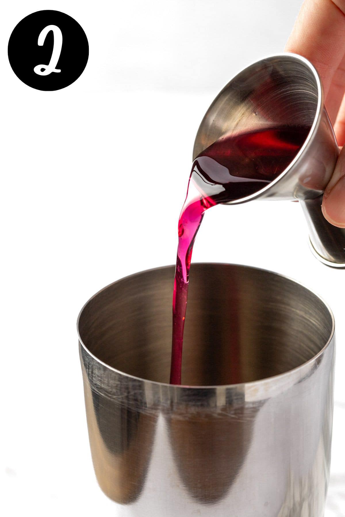 Pouring the blueberry syrup into the cocktail shaker.