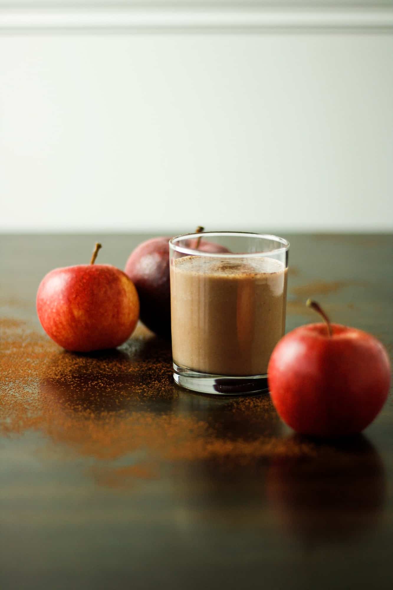 Apple chocolate smoothie on a table next to fresh apples. 