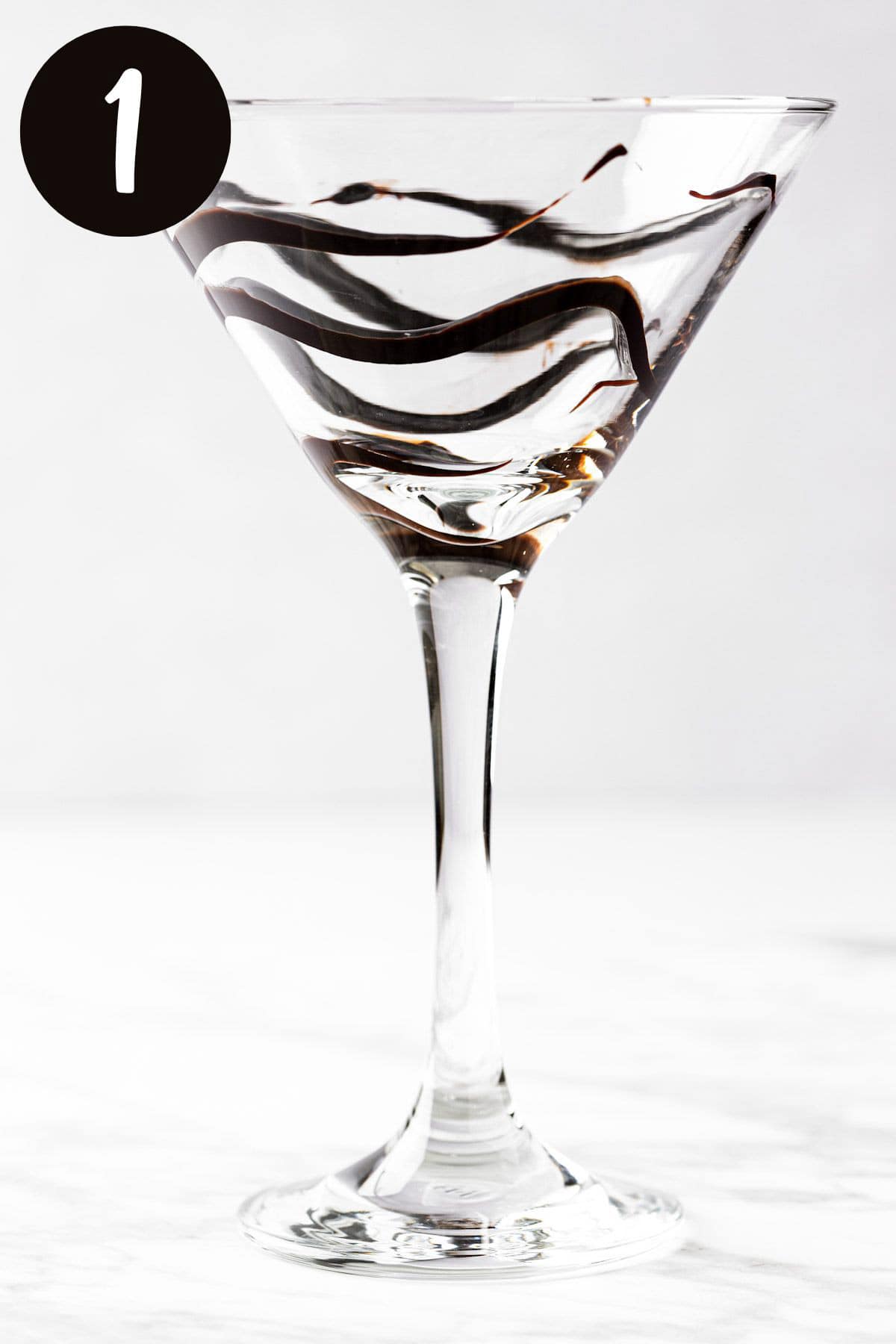 A martini glass with a drizzle of chocolate sauce around the inside of the glass.