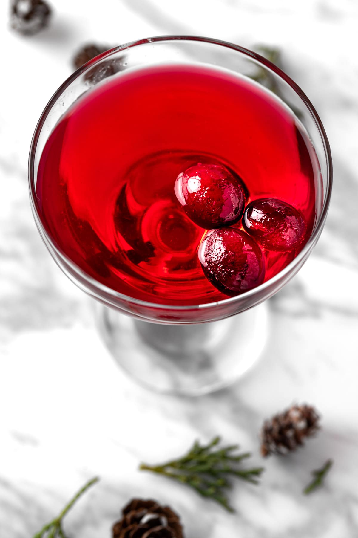 A cranberry gimlet garnished with 3 cranberries.