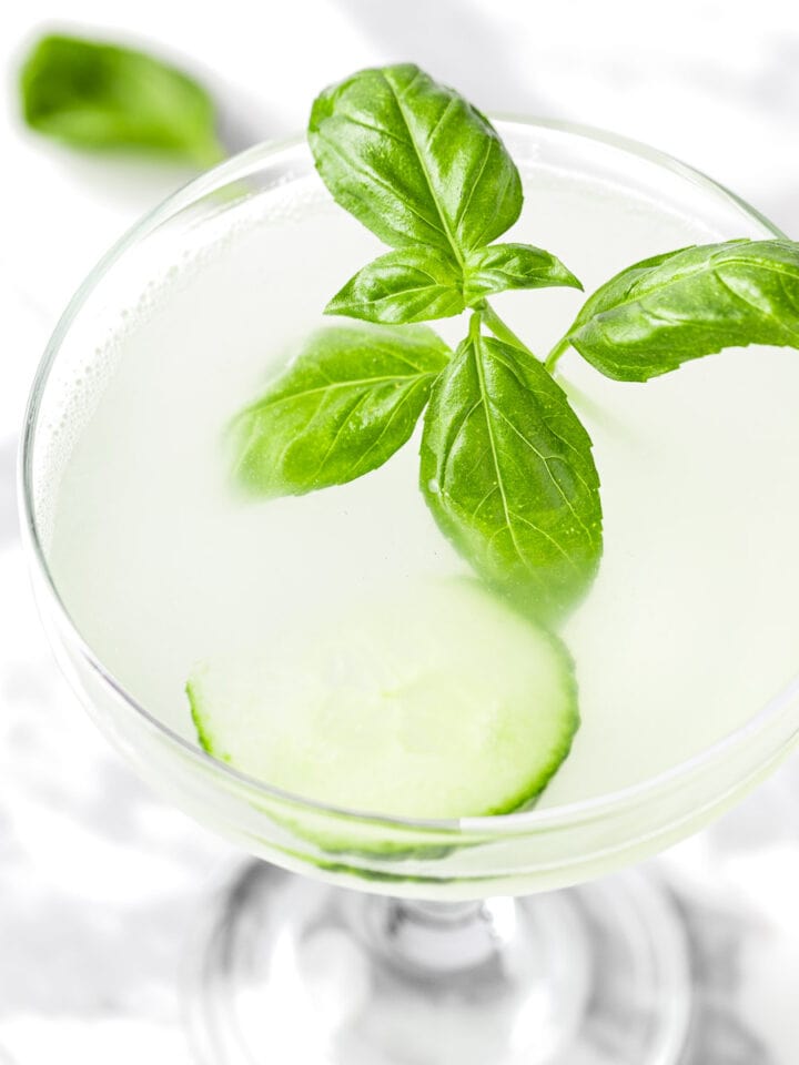 A cucumber basil gimlet garnished with cucumber slices and basil leaves.