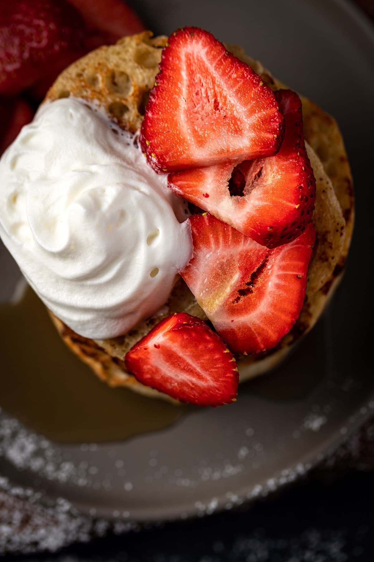 Overhead view of english muffins topped with whipped cream and strawberry slices.