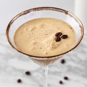 An espresso martini mocktail garnished with a cocoa rim and 3 coffee beans.