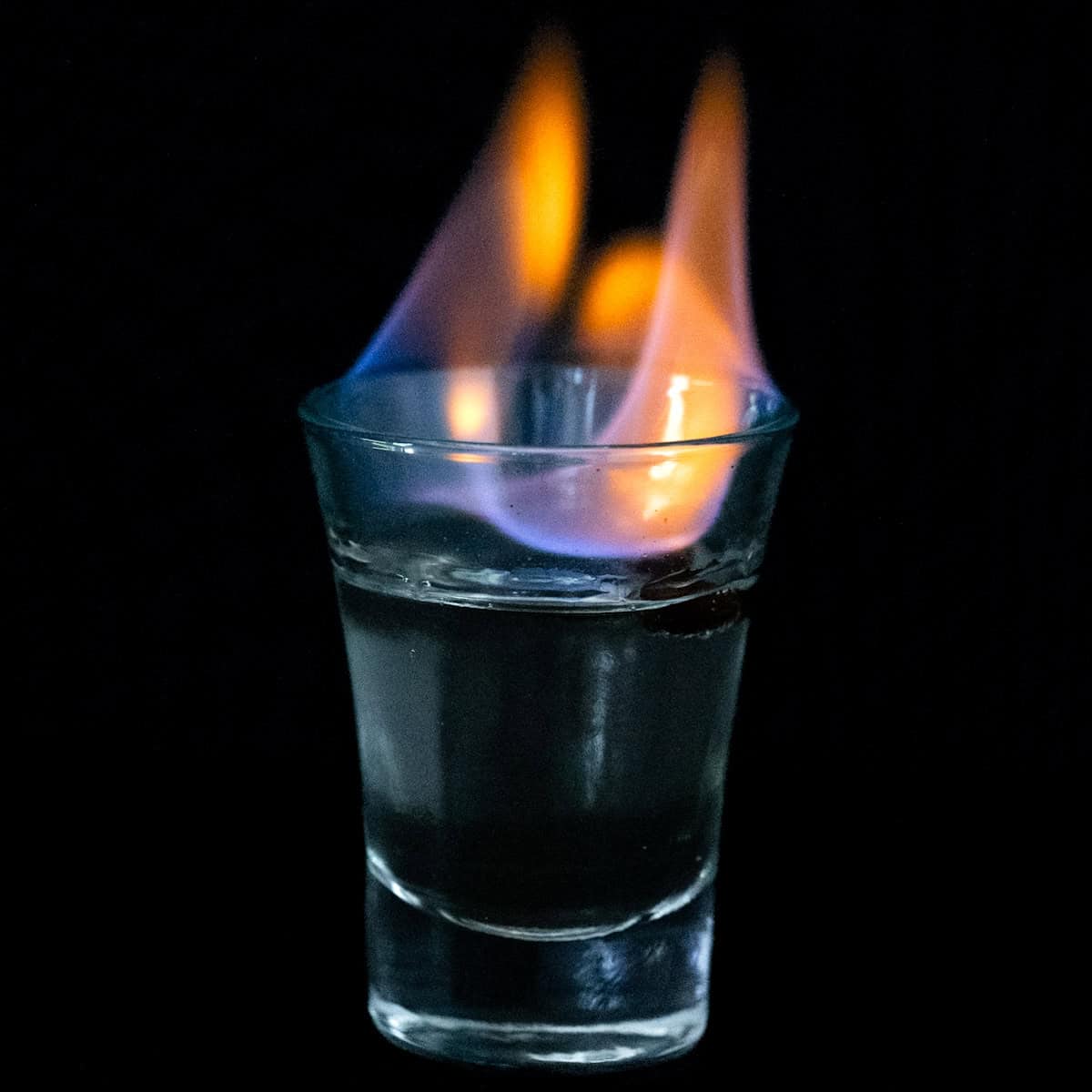 A sambuca shot on fire with an orange blue flame. 