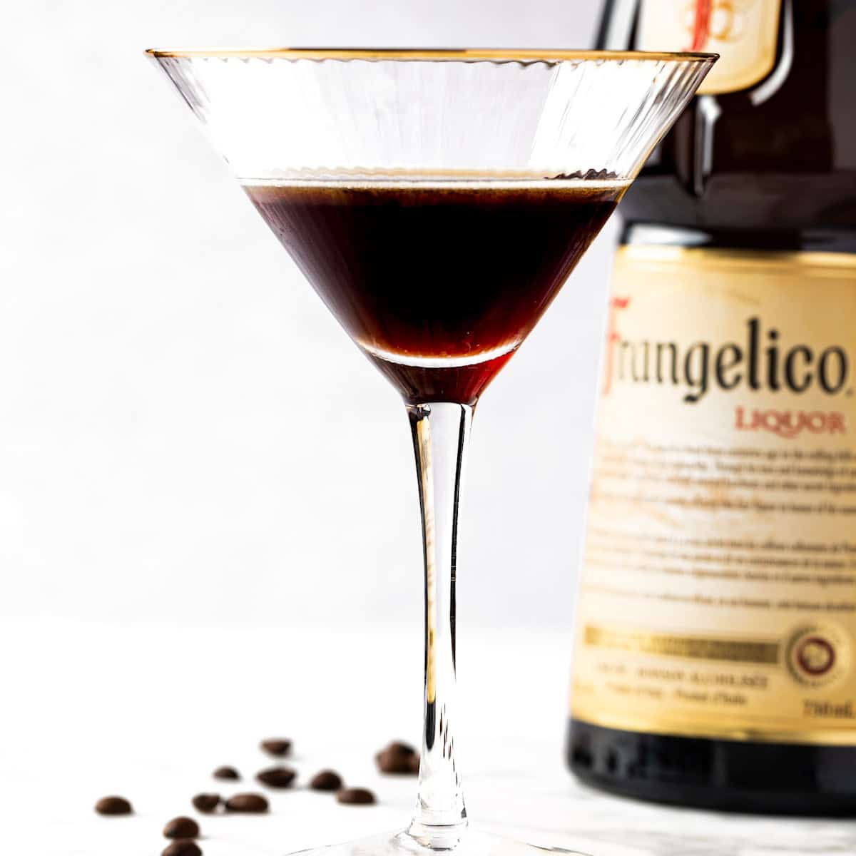 A Frangelico Espresso Martini with a bottle of Frangelico in the background.