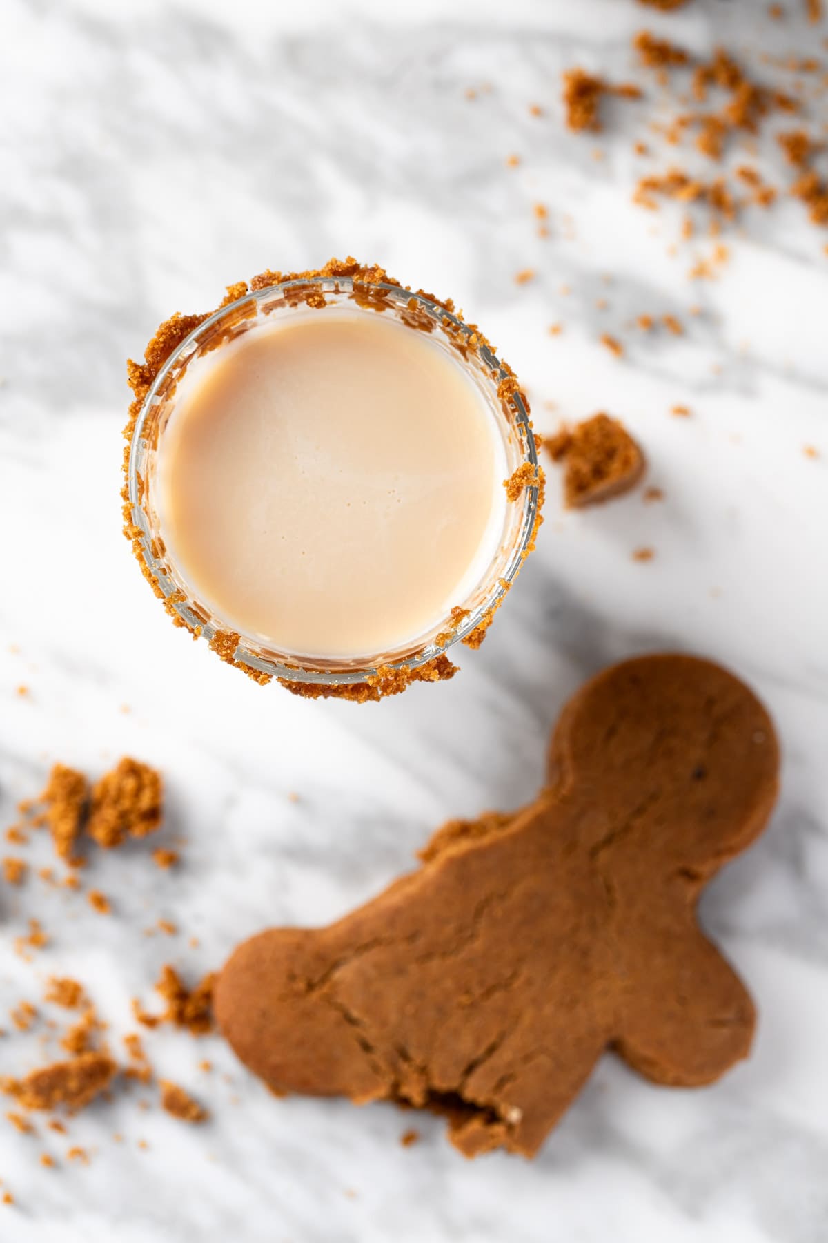 A gingerbread man shot on a white table next to half a gingerbread man cookie.