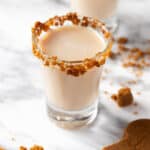Gingerbread man shots with a gingerbread cookie rim, next to crumbled gingerbread cookies.