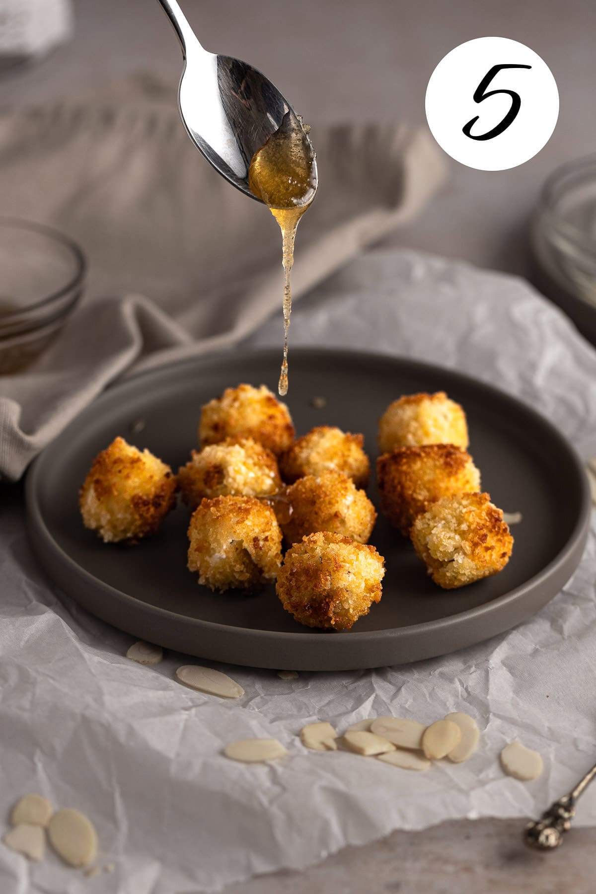 A spoonful of honey being drizzled over the croquettes.