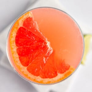 Overhead view of a grapefruit martini garnished with a half slice of grapefruit.