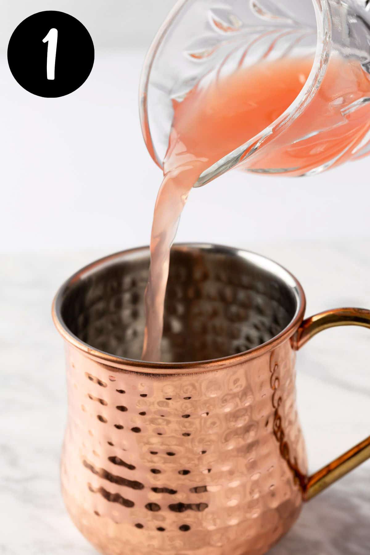 Pouring the grapefruit juice into a copper mug.