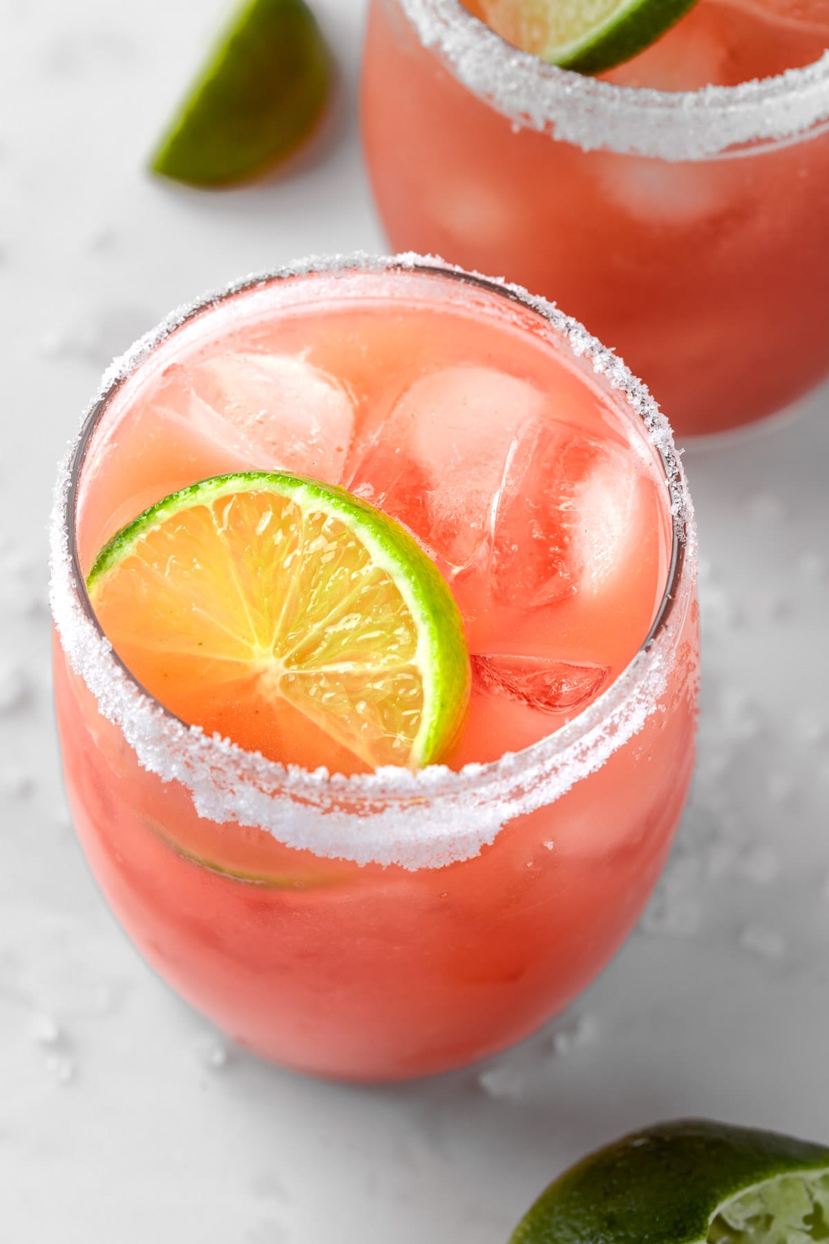 A pink guava margarita on the rocks, garnished with lime and a salted rim.