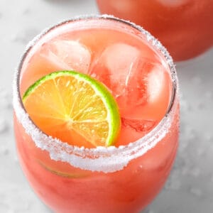 A pink guava margarita on the rocks, garnished with lime and a salted rim.
