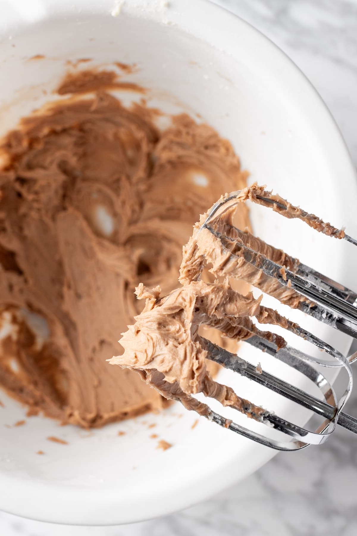 Chocolate hazelnut buttercream frosting on an electric mixer.