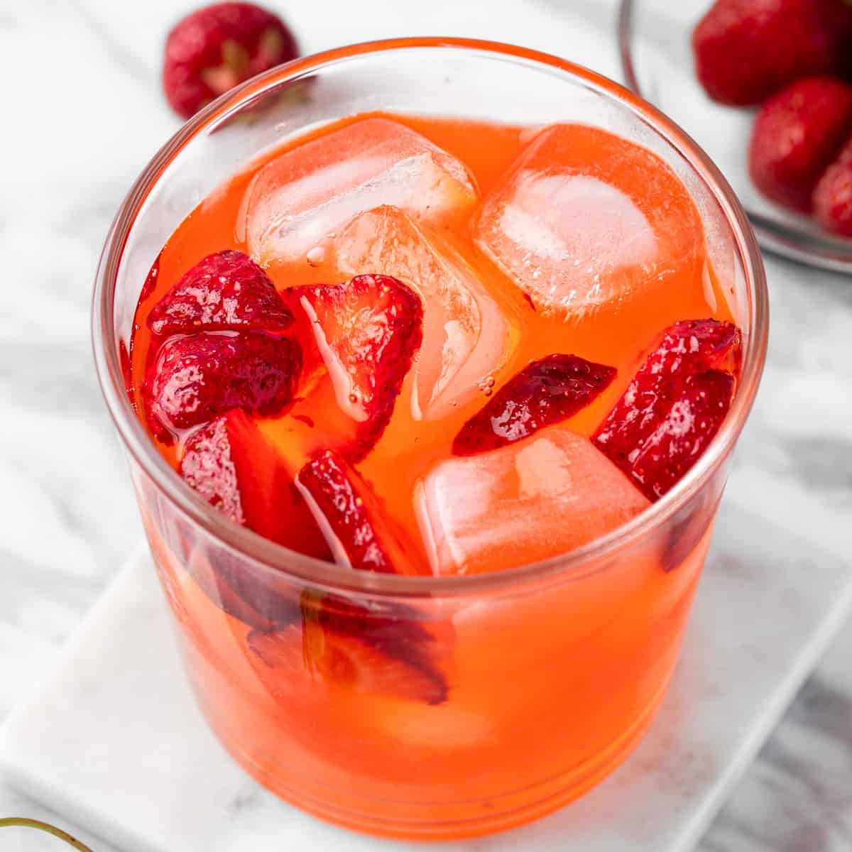 A Henny Hustle cocktail garnished with fresh strawberry slices.