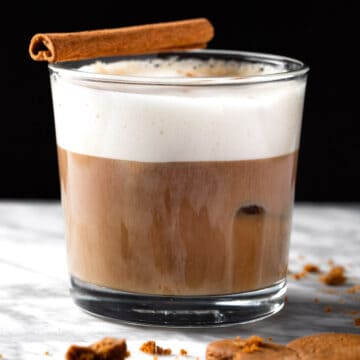 An iced gingerbread latte garnished with a cinnamon stick.